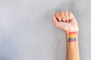 Raised fist with rainbow flag colors painted on wrist, supporting LGBTQ+ rights