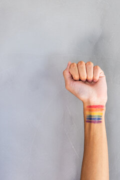Raising fist, person showing rainbow pride flag tattoo on wrist