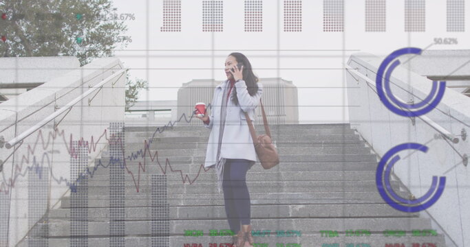 Image of graphs, trading board, biracial woman talking on phone with coffee walking downstairs