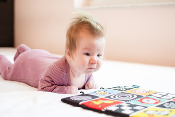 2-month-old newborn baby girl looking at high-contrast pictures during tummy time. Baby early learning. Newborn development. Newborn care concept