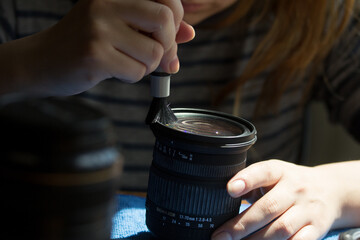 Photograph of a woman cleaning a camera lens. Concept of photography.