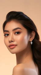 Beauty face. Woman with natural makeup and healthy skin portrait. Beautiful asian girl model touching fresh glowing hydrated facial skin on beige background closeup. Skin care concept 