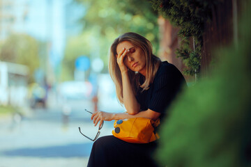 Stressed Woman Suffering a Headache Resting Outdoors. Tired adult person feeling unwell during a...