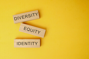 Wooden blocks with DEI text or Diversity, Equity, and Inclusion on yellow background.