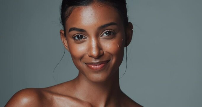 Face, skincare or Indian woman with serum for collagen in studio isolated on gray background. Portrait, smile or young model with dropper for facial cosmetics, dermatology or glow oil for beauty