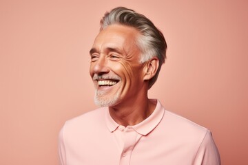 Obraz premium Portrait of a smiling senior man with grey hair. Isolated over pink background.