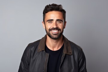 Obraz premium Portrait of a handsome man smiling at the camera while standing against grey background