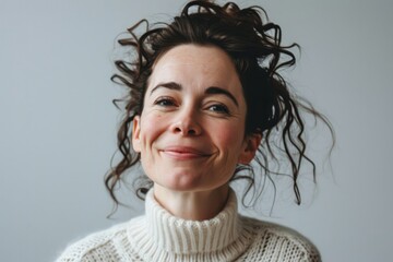 Portrait of a smiling woman in a white sweater on a gray background