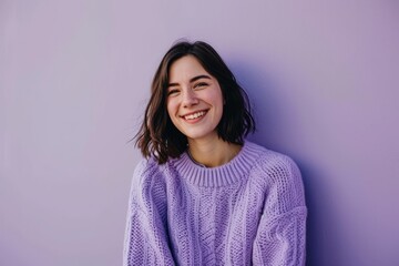 Fototapeta premium Portrait of a smiling girl in a lilac sweater on a purple background