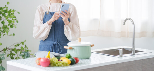 スマホで料理のレシピを調べる女性（キッチン・主婦）