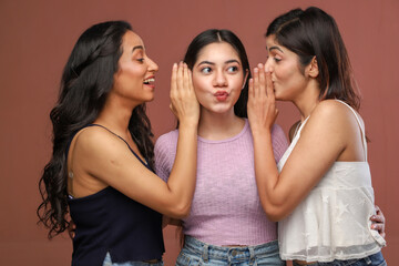 Three Confident Women Are Standing And Whispering In Each Other's Ears