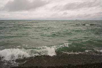 An incoming wave on the Black Sea and a pebble beach on the Sochi coast on a summer day with clouds, Sochi, Krasnodar Territory, Russia