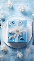 An elegantly wrapped blue gift box featuring intricate decorations like white flowers and silver accents, perfectly positioned on a matching blue and white plate setting ready for celebration.