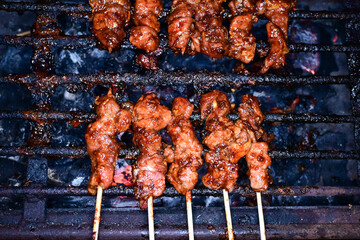 Satay is being grilled on a grill using coals and emitting smoke