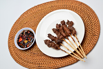Satay with peanut sauce and soy sauce topped with chili slices and shallots is an Indonesian delight. Juicy grilled meat skewers paired with rich, spicy, and savory sauces.