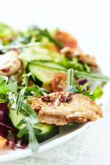  Salad with Chicken Breast, Cherry Tomatoes, Cucumber, Rocket and fresh Basil. Bright wooden background. Close up.