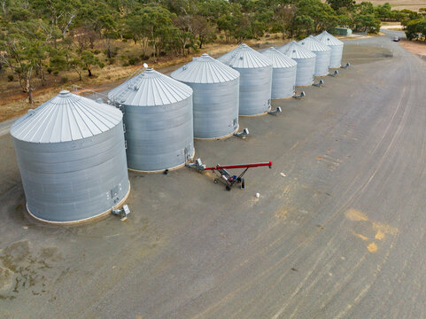 Aerial view of a line of grain storage bins and auger