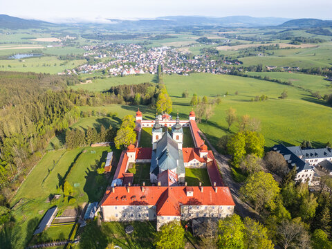 An aerial view of Hora Matky Bozi Monastery, located in Dolni Hedec near Kraliky, Czechia. The monastery is surrounded by lush greenery and a scenic landscape.