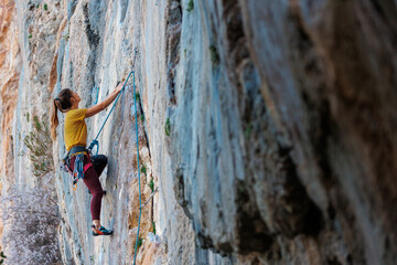 Climber overcomes challenging climbing route. A girl climbs a rock. Woman engaged in extreme sport. .