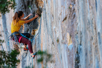 The girl climbs the rock. The climber trains on natural terrain. Extreme sport.  A woman overcomes...