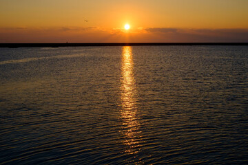 Obraz premium Golden Sunset Reflecting on Calm Ocean Waters