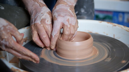 An instructor teaching a student how to make pottery clay using on throwing wheel.