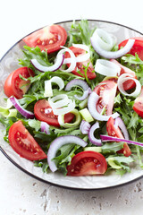 Salad with fresh tomatoes and arugula on a bright background. Close up.
