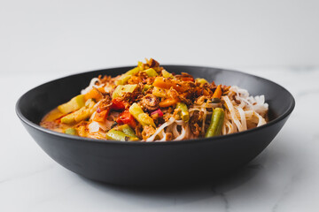 plant-based dan dan rice noodles soup with mixed vegetables and spicy sauce