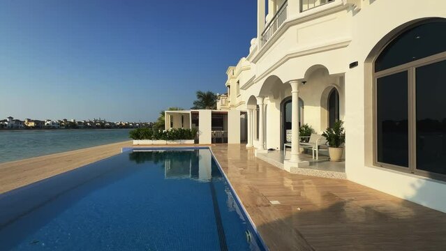 A drone flies in front of the facade of a luxury private villa with a swimming pool in Dubai