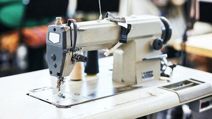 Sewing machine, needle and cotton thread for fashion in workshop for manufacturing clothes for design. Creative, tailoring and fabric equipment with material for stitches in production at factory.