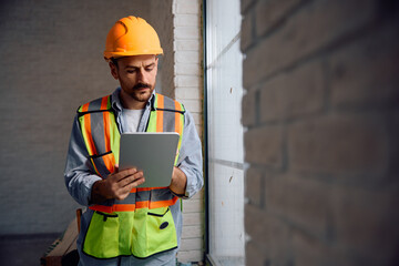 Manual worker using digital tablet at construction site.