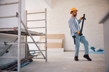 Construction site worker carrying glass in renovating home.