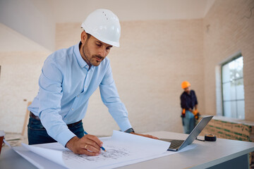 Building contractor analyzing blueprints at construction site.