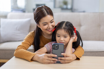 image of mother and daughter cuddling on the sofa using mobile phone waching movie online,