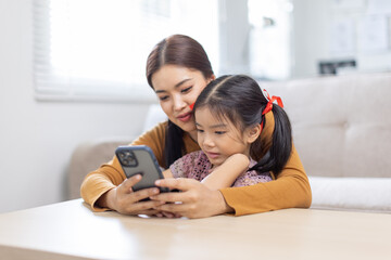 image of mother and daughter cuddling on the sofa using mobile phone waching movie online,