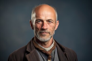 Obraz premium A man with a beard and gray hair is wearing a brown jacket and a scarf