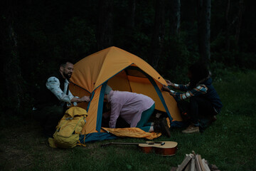 Three friends preparing the camping tent