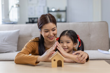 
Mother and daughter hands sheltering modern house