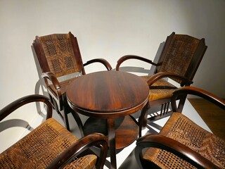 Round table with 4 chairs, crafted from dark brown wood, classic ambiance amidst a white room.