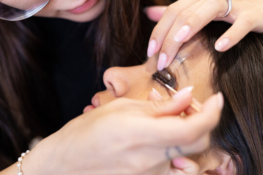 Beautician making eyelash lamination and dyeing procedures. Young latin woman in a professional beauty salon treatment.