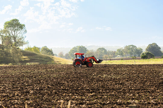Loader tractor in tilled farm paddock 