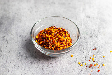 Aromatic food appetizer red chilli flakes in glass jar with ceramic background. Selective focus.  