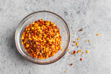 Aromatic food appetizer red chilli flakes in glass jar with ceramic background. Selective focus.  