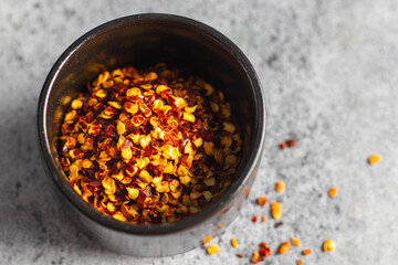 selective focus of sun dried red chilli flakes on a black bowl. 