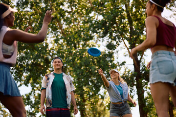 Carefree friends playing with frisbee in the park.