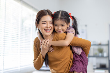 cheerful asian toddler daughter hugging happy mother Good time at home.