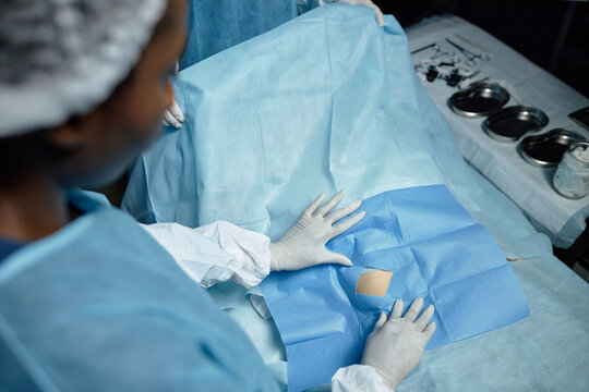 High angle view of medical assistant covering surgical site with draping in operating room copy space