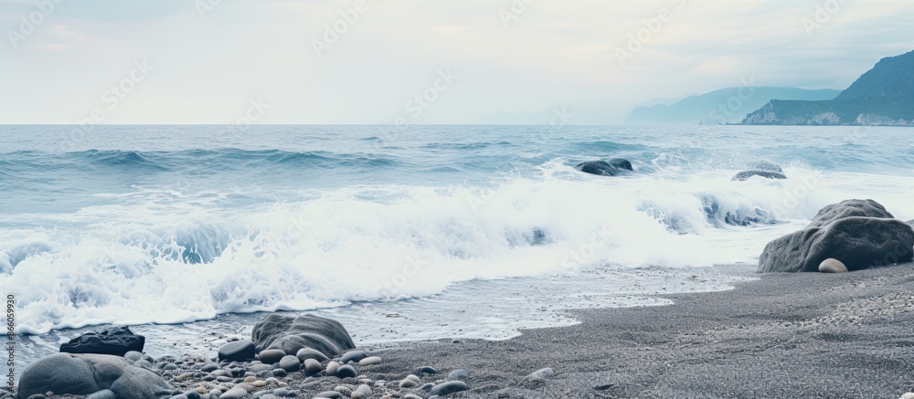 Poster Seaside scene with gray rocks amidst the sea and white foamy waves along the shore creating a tranquil ambiance for a copy space image.