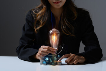 Businesswoman hand holding glowing light bulb with virtual hologram. Investment and business Innovation ideas concept