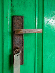 rusty door handle of green door, with key on it